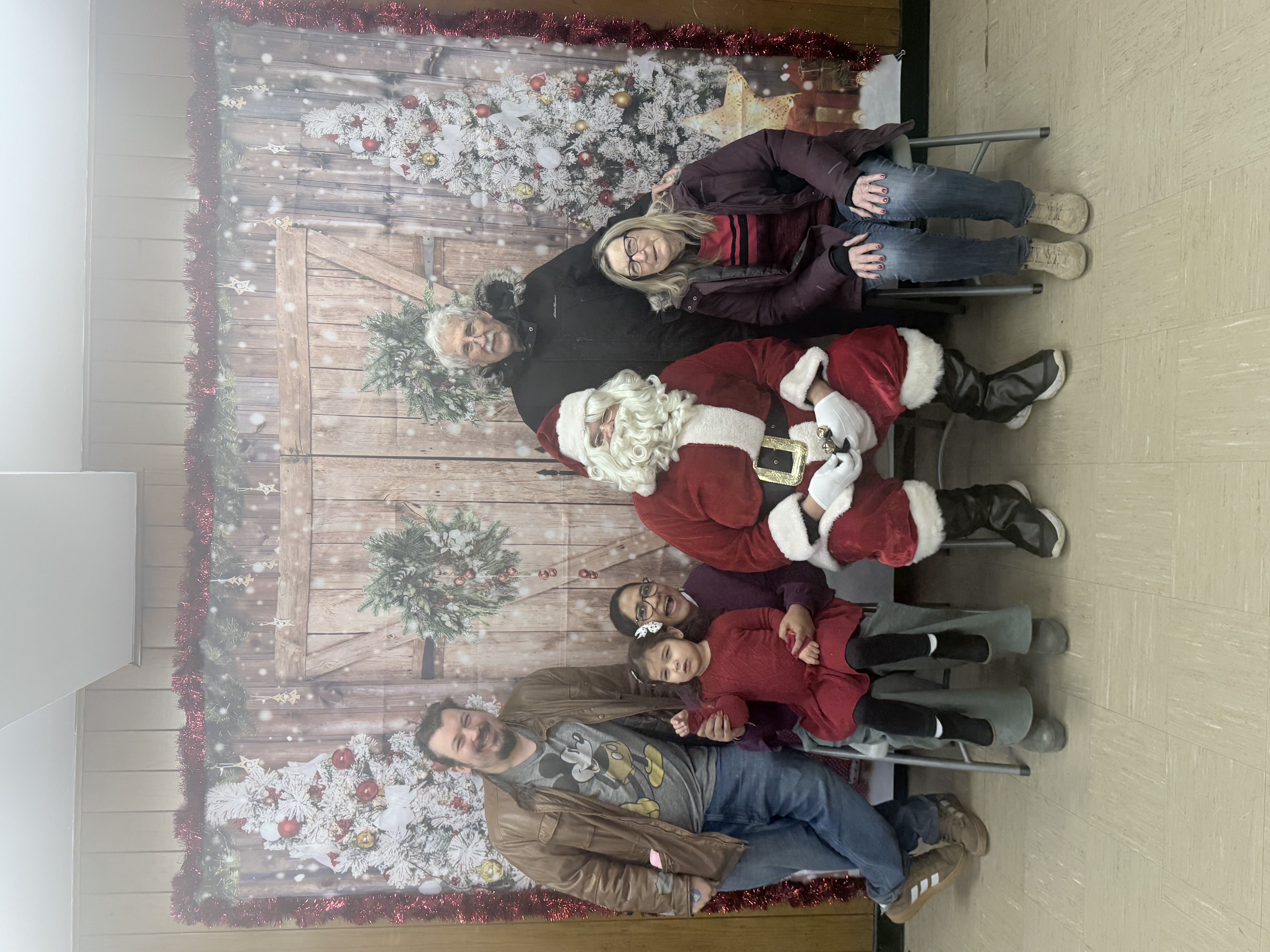 Photograph of family with Santa in front of holiday backdrop.